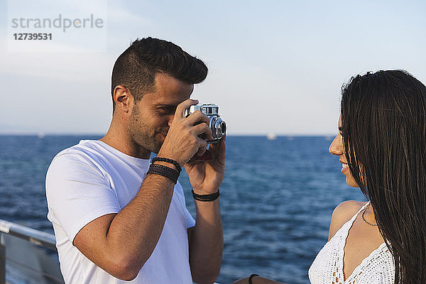 Young urban couple taking pictures by the sea