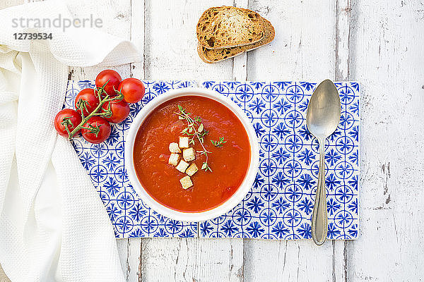 Tomato soup with roasted bread  croutons and thyme  overhead view