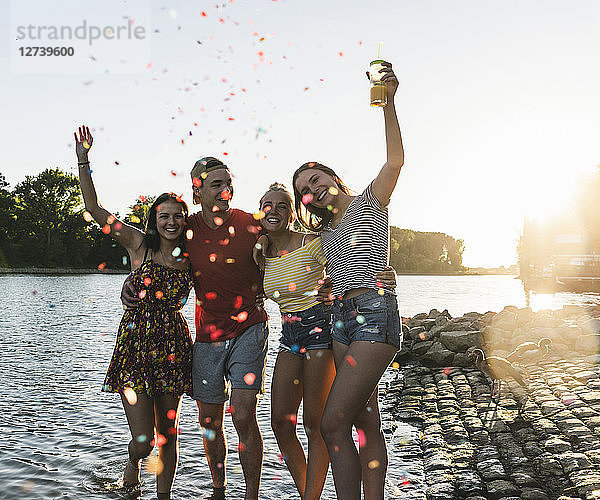 Confetti around group of happy friends having fun in a river at sunset
