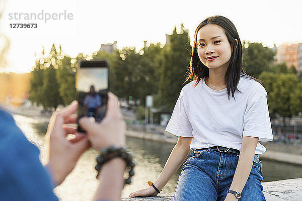 France  Paris  man taking a picture of his girlfriend at river Seine at sunset