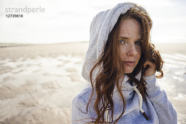 Woman wearing hood on a windy beach