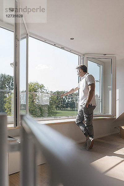 Mature man standing at the window in empty room