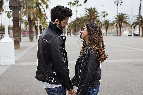 Spain  Barcelona  smiling young couple on promenade with palms