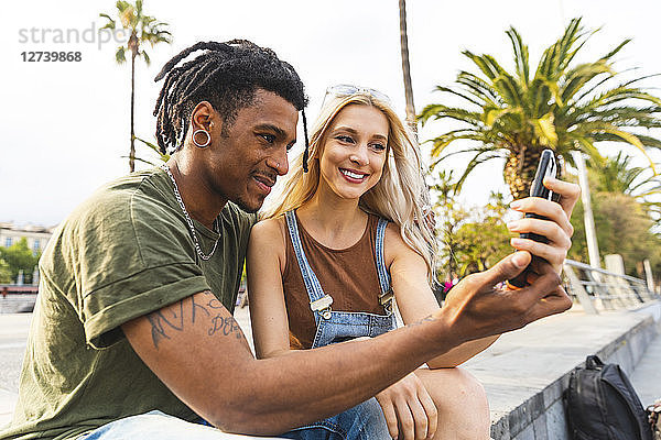 Smiling multicultural young couple looking at smartphone