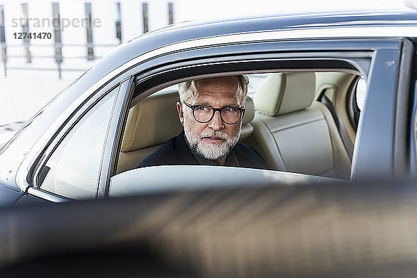 Mature businessman sitting on backseat in car  looking out of window