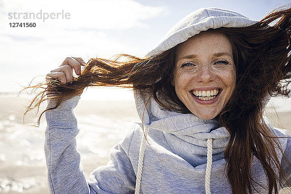 Woman having fun on a windy beach  wearing hood