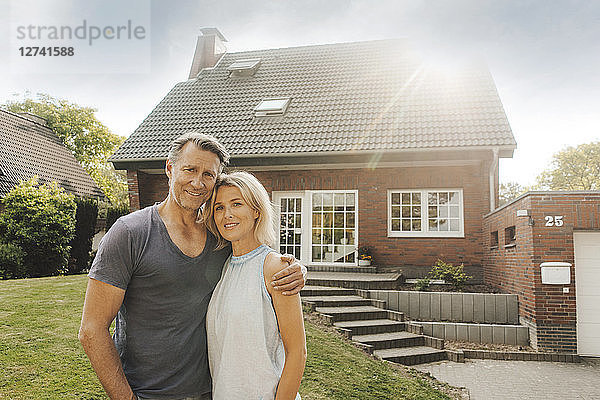 Portrait of smiling mature couple embracing in garden of their home