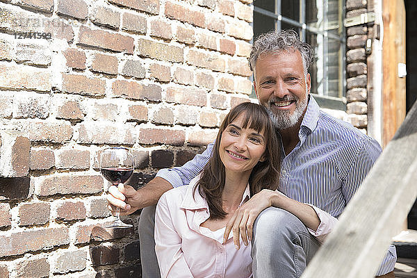 Mature couple sitting on stairs  drinking wine