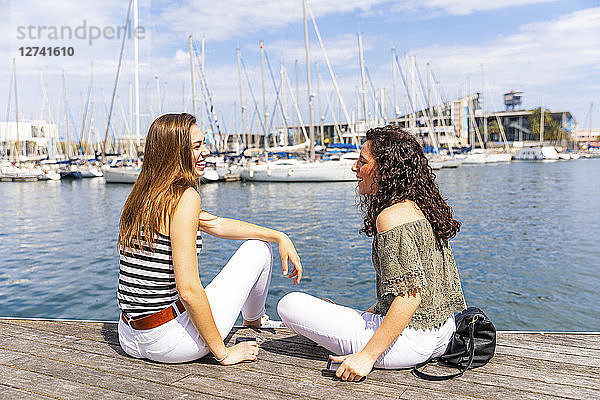 Two happy female friends talking at a marina