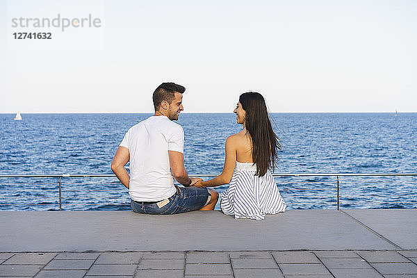 Happy young couple standing by the sea