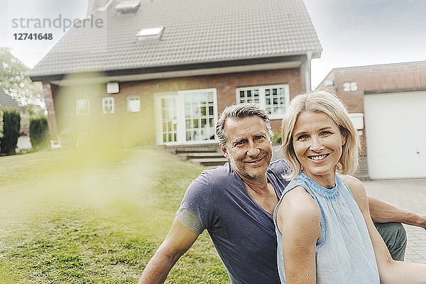 Portrait of smiling mature couple sitting in garden of their home