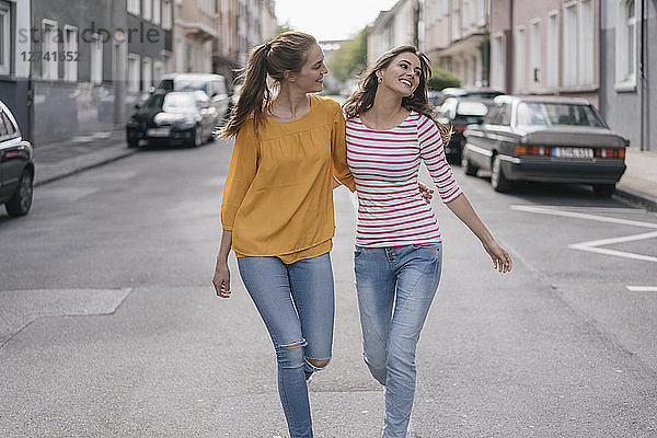 Two girlfriends having fun in the city  walking arm in arm