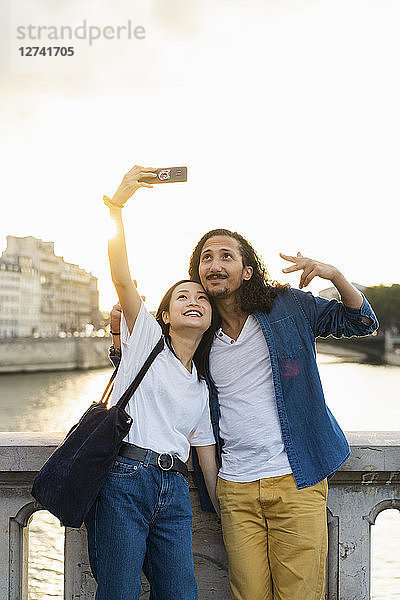 France  Paris  happy young couple taking a selfie at river Seine at sunset