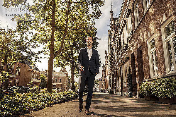 Netherlands  Venlo  confident businessman walking on pavement