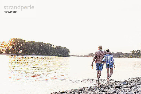 Young couple wading in river at sunset