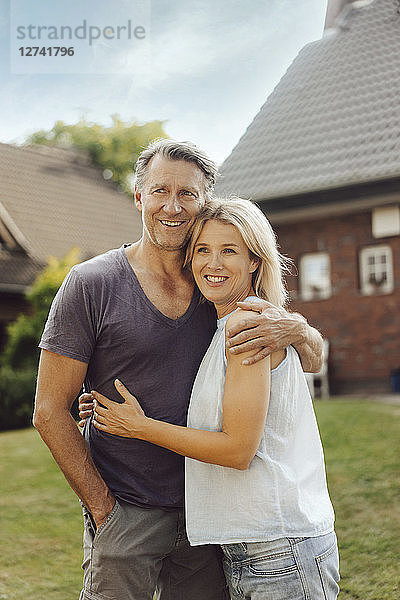 Portrait of smiling mature couple embracing in garden of their home