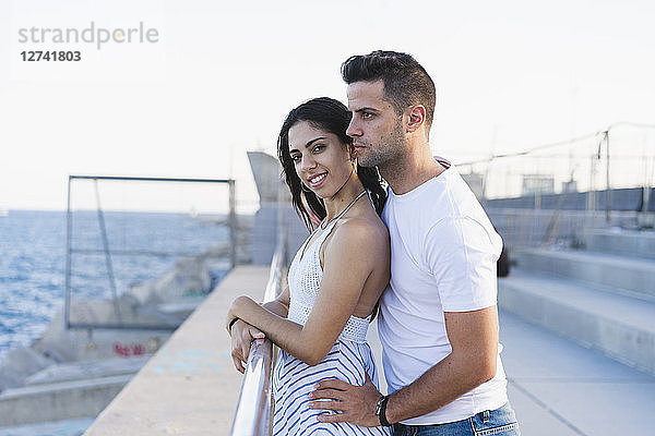 Happy young couple standing by the sea