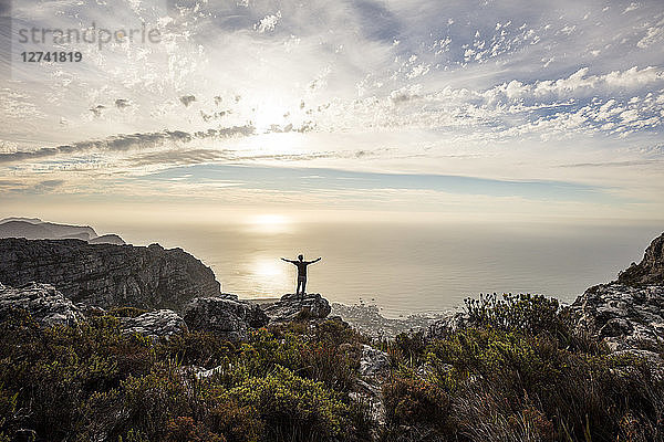 South Africa  Cape Town  Table Mountain  man standing on a rock at sunset