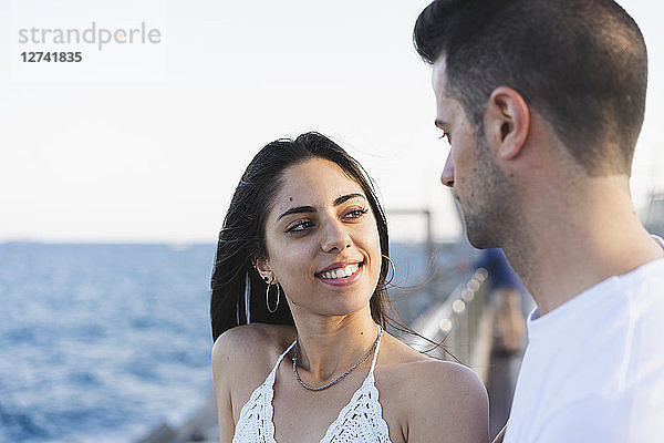 Happy young couple standing by the sea