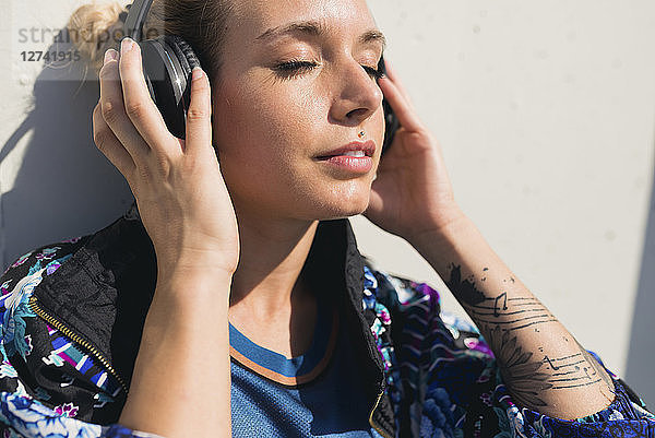 Portrait of young woman with eyes closed listening music with headphones