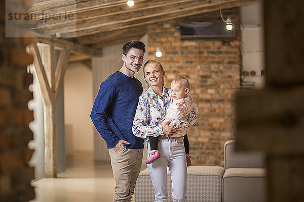Portrait of happy young parents with their baby girl at home
