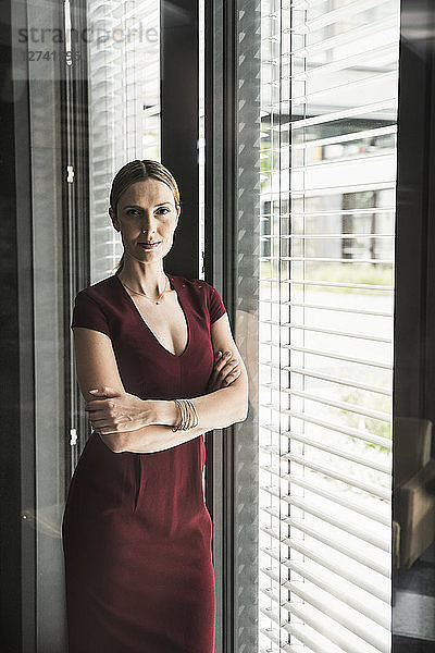 Woman wearing burgundy dress standing at the window