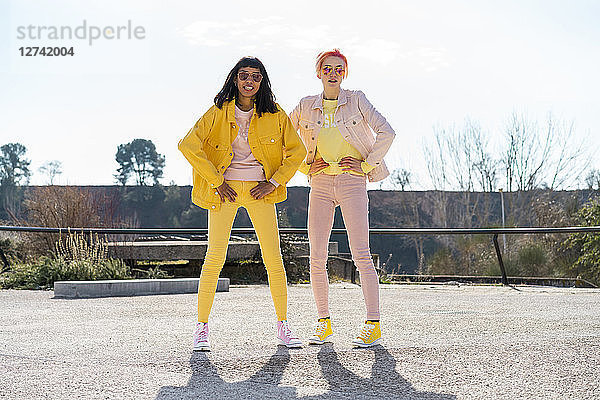 Two alternative friends wearing yellow and pink jeans clothes  posing