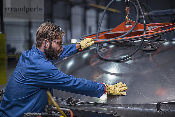 Worker in steel factory inspecting a tank