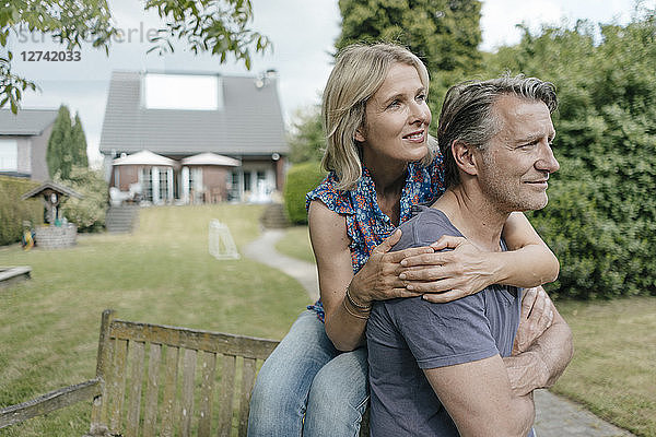 Smiling mature couple embracing in garden of their home