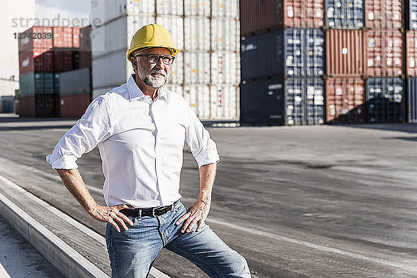Businessman at cargo harbour  wearing safety helmet  portrait