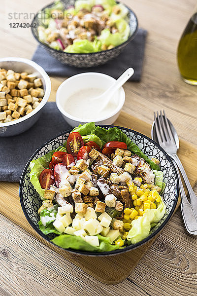 Bowl of Caesar salad with meat  corn and tomatoes