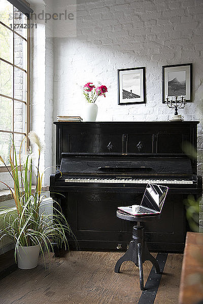 Piano with laptop on a stool in comfortable loft apartment