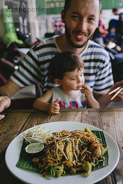 Thailand  Father and daughter eating delicious pad thai dish on a street restaurant