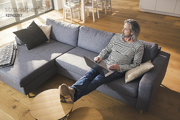 Senior man sitting on couch  using laptop