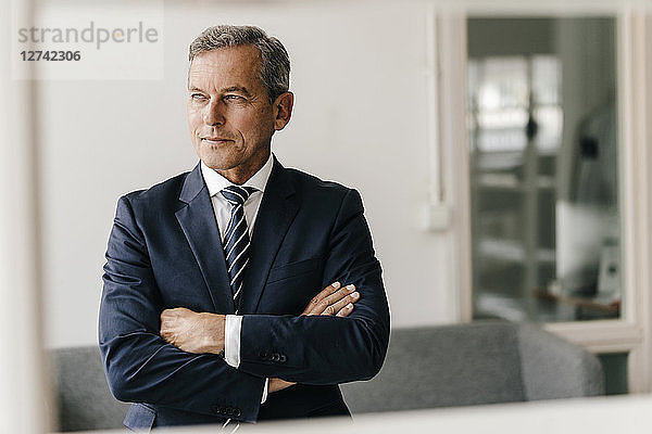 Portrait of mature businessman with arms crossed in his office