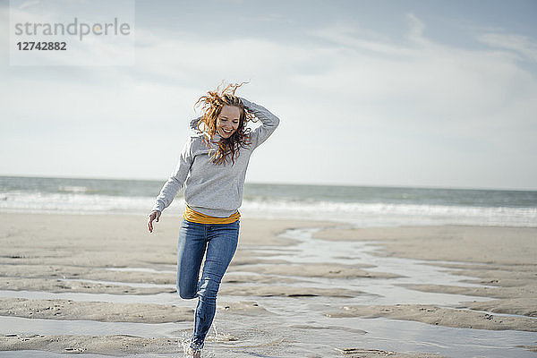 Happy woman having fun at the beach  running at the sea