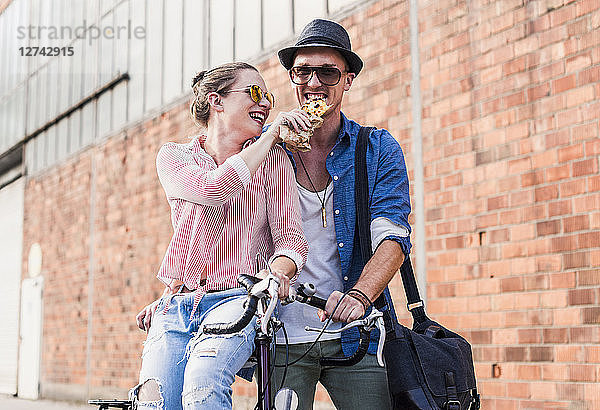 Happy young couple with bicycle sharing a snack