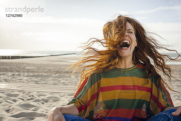 Woman sitting on the beach  screaming for joy