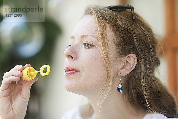 Young woman blowing soap bubble
