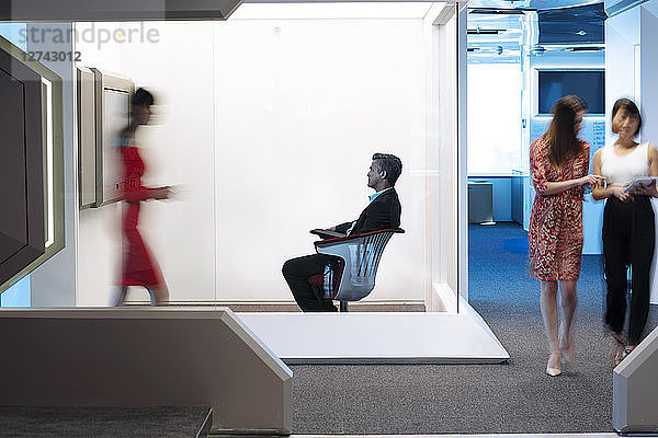 Businessman sitting chair on a busy office floor  working