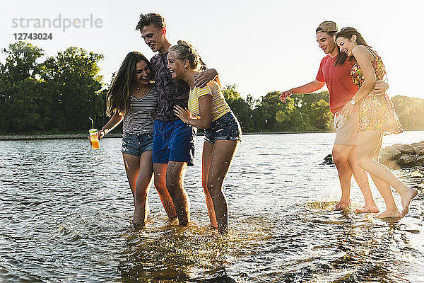 Group of happy friends in a river at sunset