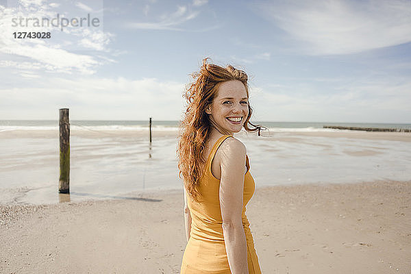 Portrait of a redheaded woman  laughing happily on the beach