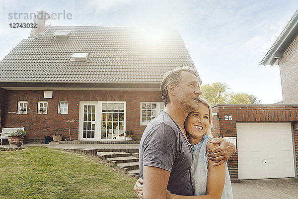 Smiling mature couple embracing in garden of their home