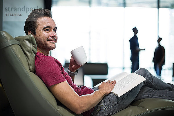 Man in office sitting in armchair  reading a book