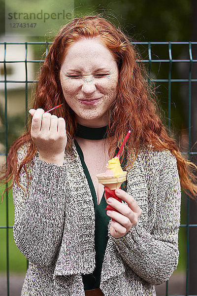 Portrait of freckled redheaded woman eating icecream