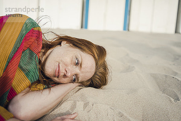 Redheaded woman resting in sand on the beach