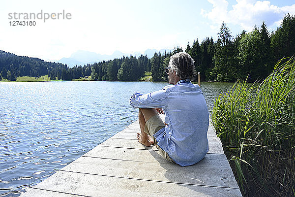 Germany  Mittenwald  mature man relaxing on jetty at lake