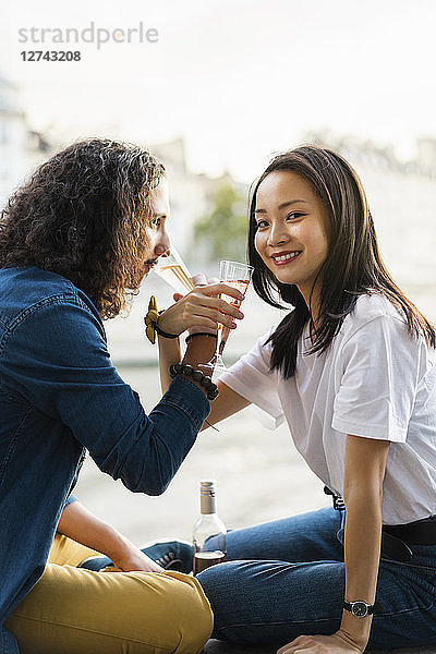 Young couple drinking champagne at the riverside