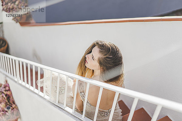 Young woman wearing a wedding dress  sitting on stairs