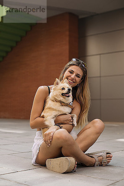 Smiling young woman sitting  holding her dog